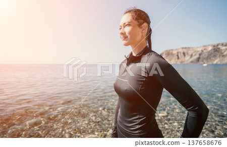 Woman Ocean Beach Seashore - Looking out at the ocean, a woman stands on a rocky beach. 137658676