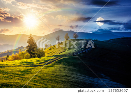 countryside landscape in mountains. day meet night. sun and moon over rural picture of wooden fence near dirt road through grassy fields on rolling hills. scenery with distant ridge during springtime 137658697