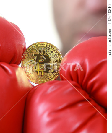 Man in boxing gloves holding bitcoin Man in boxing gloves holding bitcoin 137658816