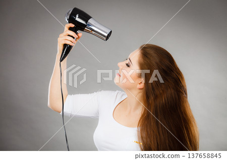 Woman drying her hair using hair dryer Woman drying her hair using hair dryer 137658845