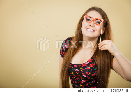 Happy woman holding fake eyeglasses on stick Happy woman holding fake eyeglasses on stick 137658846