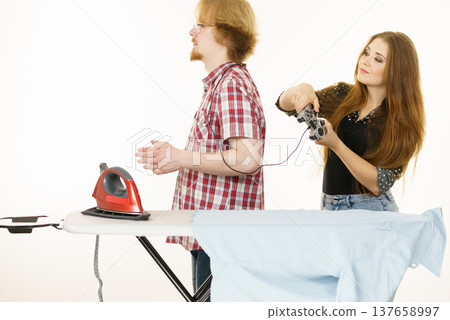 Woman controling man to do ironing Woman controling man to do ironing 137658997