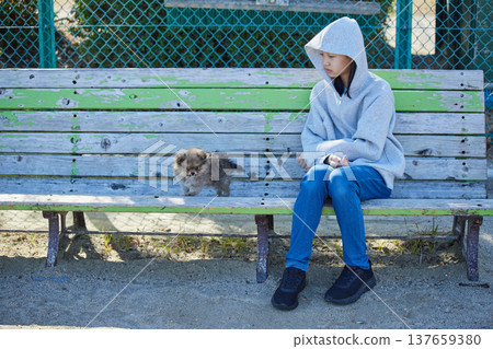 A teenage girl playing with a cute Pomeranian puppy in a park on a sunny spring day. 137659380