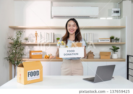 Food Donation. A young woman organizing food donations at a community center. 137659425