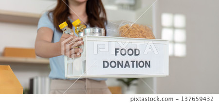 Food Donation Process. Woman presenting a basket of food donations for community support. 137659432
