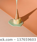 Melting ice cream cone on a pastel surface under bright lighting during the day 137659603