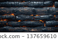 Detail texture of charred wood with glowing embers showing burnt areas and wood grain in a close view displayed against a dark background 137659610