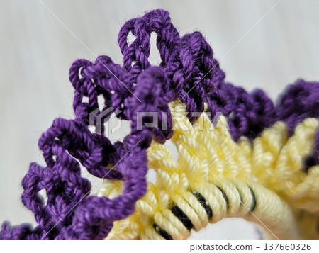 Handmade knitting: Hand-knitted lace scrunchie stitches in purple and pastel yellow. Handmade knitting: Hand-knitted lace scrunchie stitches in purple and pastel yellow. 137660326