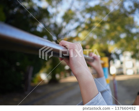 圖片顯示的是一個十幾歲女孩在春日午後於公園的單槓上快樂玩耍的雙手。 圖片顯示的是一個十幾歲女孩在春日午後於公園的單槓上快樂玩耍的雙手。 137660492