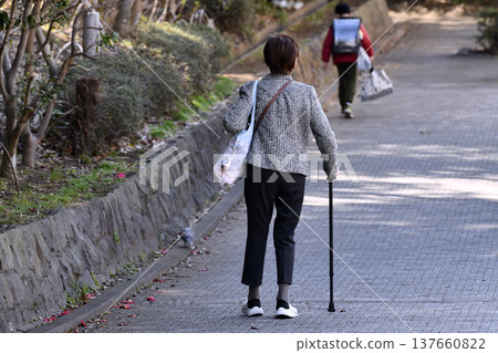 An elderly woman with a cane (wearing a mask) on a hilly sidewalk in Yokohama, Japan... What is life...? = Yokohama City An elderly woman with a cane (wearing a mask) on a hilly sidewalk in Yokohama, Japan... What is life...? = Yokohama City 137660822