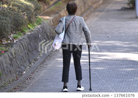 An elderly woman with a cane (wearing a mask) on a hilly sidewalk in Yokohama, Japan... What is life...? = Yokohama City 137661076