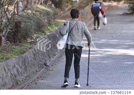 An elderly woman with a cane (wearing a mask) on a hilly sidewalk in Yokohama, Japan... What is life...? = Yokohama City An elderly woman with a cane (wearing a mask) on a hilly sidewalk in Yokohama, Japan... What is life...? = Yokohama City 137661114