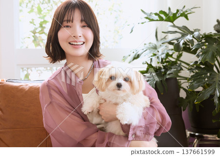 A smiling woman holding a Maltese dog; a lifestyle with pets; life with a dog. A smiling woman holding a Maltese dog; a lifestyle with pets; life with a dog. 137661599