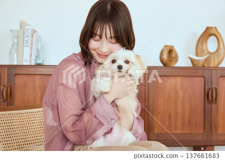 一位女士擁抱一隻馬爾濟斯犬:與寵物共度一段寧靜舒適的時光。 一位女士擁抱一隻馬爾濟斯犬:與寵物共度一段寧靜舒適的時光。 137661683