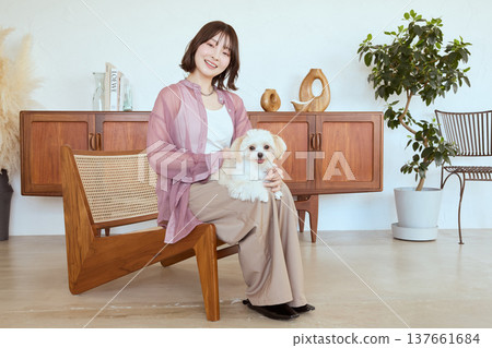 A woman sits with a Maltese dog on her lap; a natural lifestyle with pets. A woman sits with a Maltese dog on her lap; a natural lifestyle with pets. 137661684
