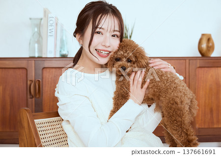 A woman holding a toy poodle; a lifestyle with pets. A woman holding a toy poodle; a lifestyle with pets. 137661691