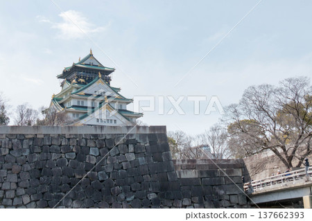 大阪城主塔和高聳入雲的巨大石牆映襯著蔚藍的天空。 大阪城主塔和高聳入雲的巨大石牆映襯著蔚藍的天空。 137662393