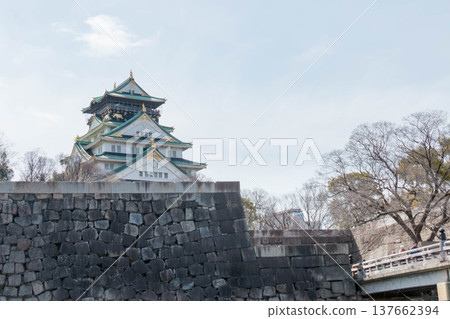 大阪城主塔和高聳入雲的巨大石牆映襯著蔚藍的天空。 137662394