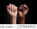 Two raised fists, one light-skinned with nude polish and one dark-skinned with pink polish. Symbolizes strength and unity for International Women's Day. 137664933