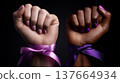 Two raised fists, one light-skinned with a pink ribbon and the other dark-skinned with a purple ribbon. Symbolizes strength and unity for International Women's Day. 137664934