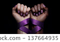 Two hands, one light-skinned with purple nails and one dark-skinned with natural nails, are tied together with a purple ribbon. Symbolizes feminism and unity. 137664935