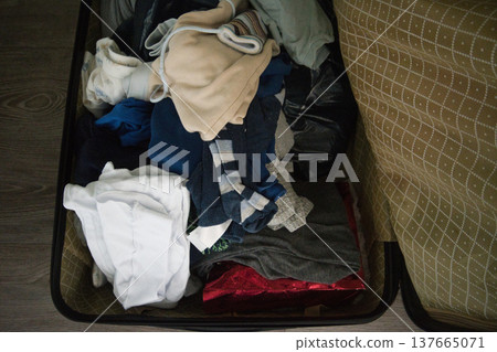 Open suitcase with messy children clothes and toys, family travel packing chaos Open suitcase with messy children clothes and toys, family travel packing chaos 137665071