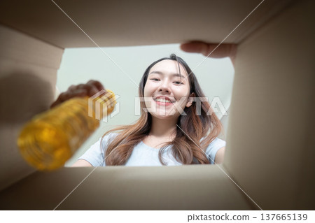 Food Donation. A woman smiling while looking into a donation box. 137665139