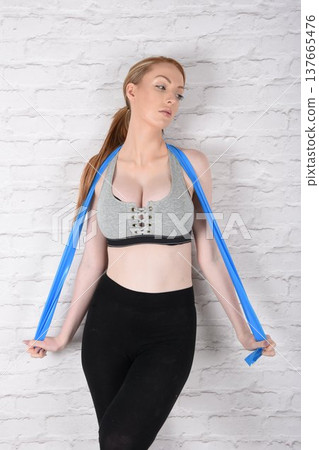 Tall, attractive redhead girl in black leggings and a grey sports bra, exercising at the gym Tall, attractive redhead girl in black leggings and a grey sports bra, exercising at the gym 137665476