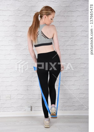 Tall, attractive redhead girl in black leggings and a grey sports bra, exercising at the gym 137665478