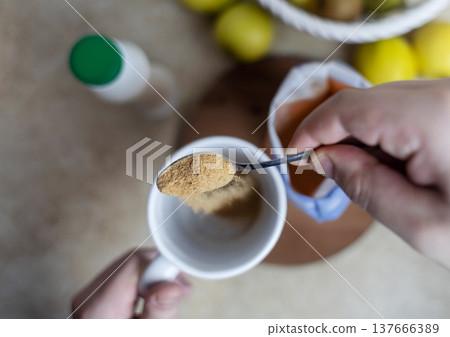 Person adding apple fiber powder to a glass of yogurt, surrounded by fresh apples and walnuts. Healthy prebiotic supplement for gut health, digestion and weight management. 137666389