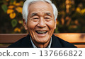 Happy elderly Asian man with white hair laughing joyfully outdoors in autumn park setting wearing dark jacket 137666822