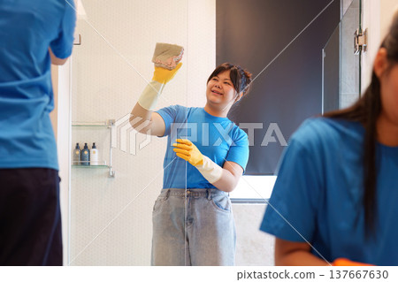 Team Cleaning. Happy woman cleaning the bathroom with a smile. 137667630