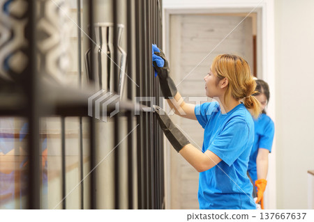 Team Cleaning. Two women dusting shelves in a modern interior. 137667637