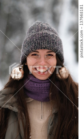 A beautiful young woman in winter clothes is happily spending her free time in a snowy forest. She enjoys the first snow. Active winter recreation. A beautiful young woman in winter clothes is happily spending her free time in a snowy forest. She enjoys the first snow. Active winter recreation. 137668181