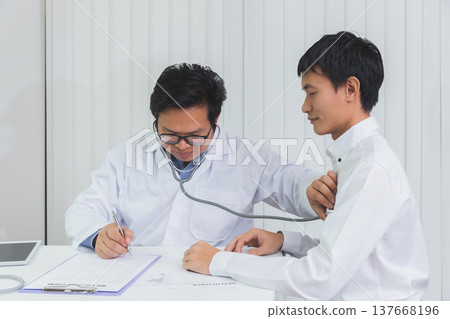 Doctor Checking Patient With Stethoscope. Doctor listening to patient chest with stethoscope in his office at the hospital. 137668196