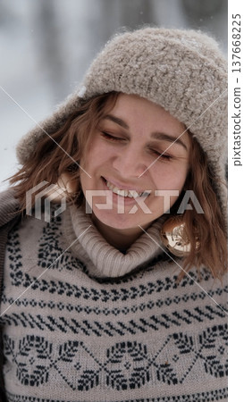 A beautiful woman in winter clothing enjoys her free time in a snowy forest. Portrait of a woman enjoying the first snow. Active winter recreation. A beautiful woman in winter clothing enjoys her free time in a snowy forest. Portrait of a woman enjoying the first snow. Active winter recreation. 137668225