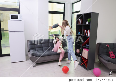 Friends enjoying a playful afternoon in a cozy living room filled with colorful balloons and laughter in a sunlit apartment Friends enjoying a playful afternoon in a cozy living room filled with colorful balloons and laughter in a sunlit apartment 137668505
