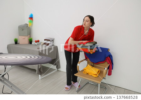Sorting and folding colorful clothes in a cozy, bright laundry room during a sunny afternoon Sorting and folding colorful clothes in a cozy, bright laundry room during a sunny afternoon 137668528