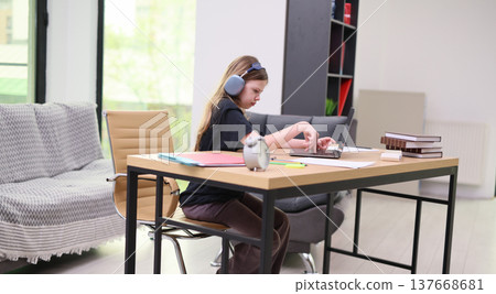 Focused student engaged in homework at a modern workspace with natural light and cozy decor 137668681