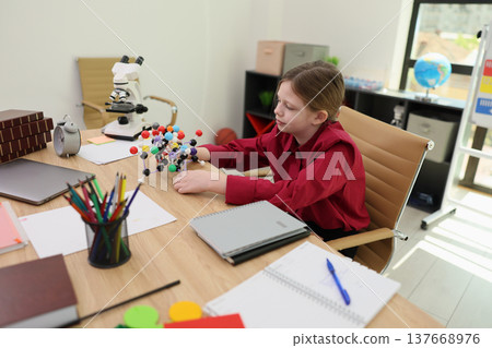 Young scientist explores molecular structures with colorful models in a bright, engaging study environment Young scientist explores molecular structures with colorful models in a bright, engaging study environment 137668976