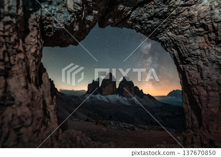 Rocky cave Grotta delle Tre Cime framing Tre Cime di Lavaredo mountain peaks with Milky Way in Dolomites, Italy Rocky cave Grotta delle Tre Cime framing Tre Cime di Lavaredo mountain peaks with Milky Way in Dolomites, Italy 137670850