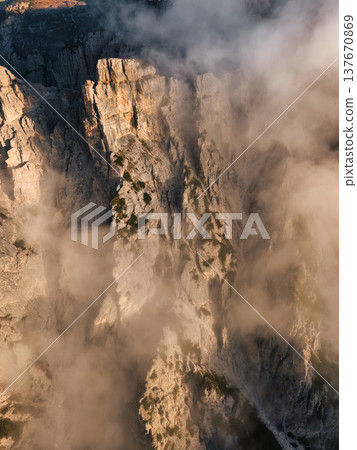 Rugged rocky mountain steep with sunrise fog in Tre Cime, Dolomites Rugged rocky mountain steep with sunrise fog in Tre Cime, Dolomites 137670869