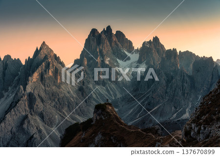 Alpine landscape of Cadini di Misurina with rugged mountain peak and male tourist hiking during sunset in Dolomites, Italy Alpine landscape of Cadini di Misurina with rugged mountain peak and male tourist hiking during sunset in Dolomites, Italy 137670899
