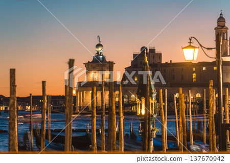 Basilica di Santa Maria della Salute with gondola pier and illuminated street lamp by Grand Canal in Venice, Italy Basilica di Santa Maria della Salute with gondola pier and illuminated street lamp by Grand Canal in Venice, Italy 137670942