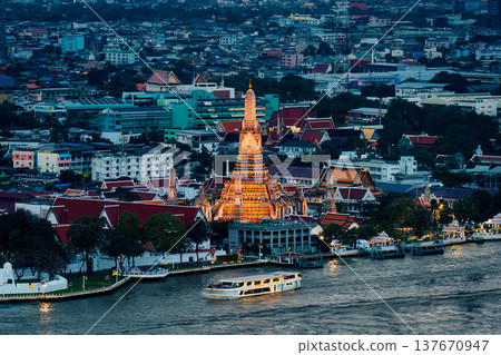 Wat Arun temple illuminated with urban houses and Chao Phraya river at dusk in Bangkok 137670947