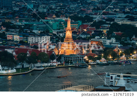 Wat Arun temple illuminated with urban houses and Chao Phraya river at dusk in Bangkok Wat Arun temple illuminated with urban houses and Chao Phraya river at dusk in Bangkok 137671019