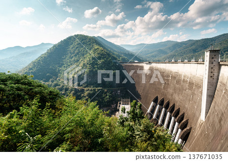 Large concrete dam landscape with mountain and forest hill in sunny day Large concrete dam landscape with mountain and forest hill in sunny day 137671035