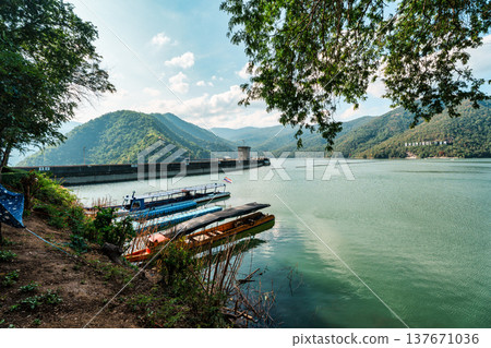 Large concrete dam with wooden boat on sunny day in Tak, Thailand Large concrete dam with wooden boat on sunny day in Tak, Thailand 137671036