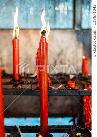 Row of lit red candles in metal holders symbolizing faith, devotion, and traditional worship ritual Row of lit red candles in metal holders symbolizing faith, devotion, and traditional worship ritual 137671042