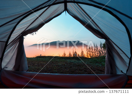 View from inside backpacking tent of sunrise over mountain mist and pine tree in valley View from inside backpacking tent of sunrise over mountain mist and pine tree in valley 137671111